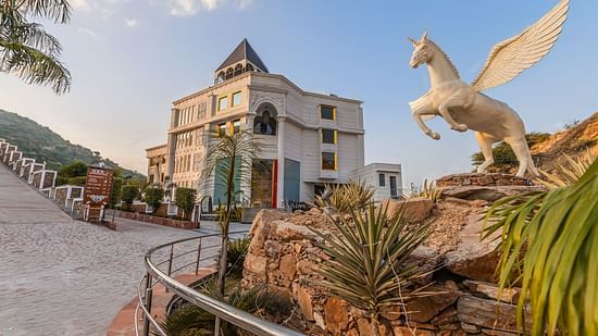An image of a building with a drive way down and a statue of a horse in the side